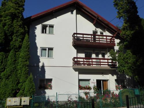 een wit huis met een rood balkon bij Pension Tui in Sinaia