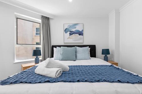 a bedroom with a large bed with blue sheets and pillows at Discover Bond Street in Sydney