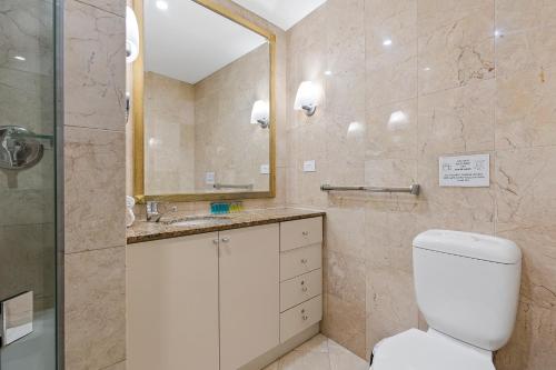 uma casa de banho com um WC, um lavatório e um espelho. em Discover Bond Street em Sydney