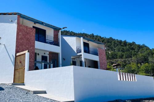 a house with a white wall and a fence at Casa De Campo Mirador H&L in San Antonio de las Alzanas