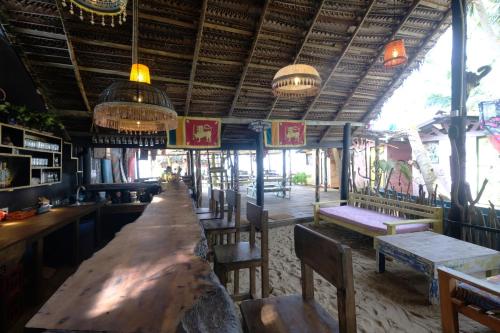 a long table in a restaurant with chairs and lights at Bara Beach Home in Galle