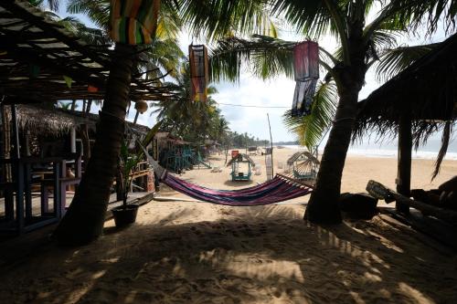 a hammock on a beach with palm trees at Bara Beach Home in Galle
