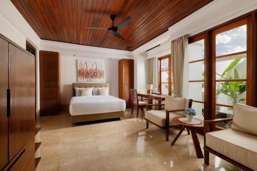 a bedroom with a bed and a table in a room at Jimbaran Beach Villas by Nakula in Jimbaran