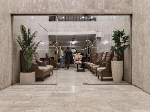a lobby with a waiting room with couches and plants at الساعه 60 الفندقيه in Dammam