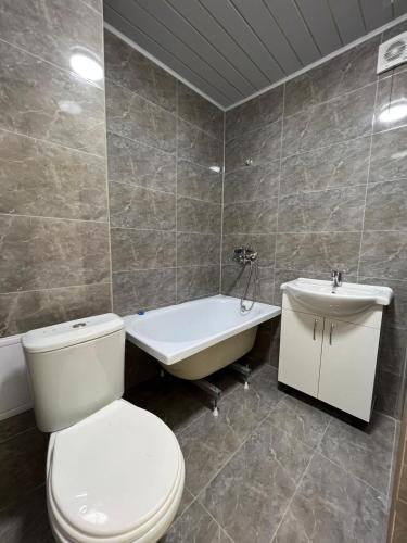 a bathroom with a toilet and a sink and a tub at Парни in Qyzylorda