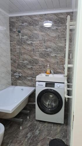 a bathroom with a washing machine and a bath tub at Парни in Qyzylorda