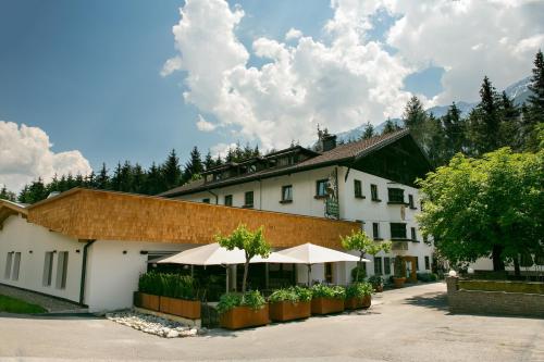un gran edificio blanco con una sombrilla delante en Hotel Gasthof Hirschentenne en Stams