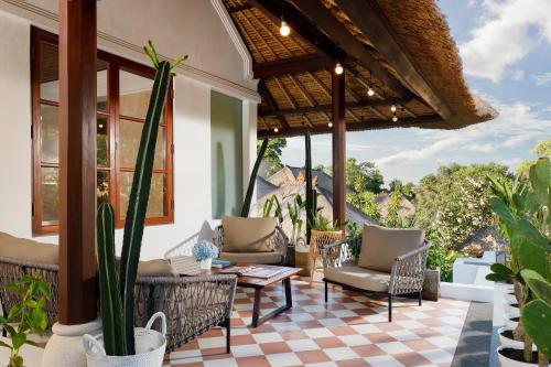 a patio with chairs and a table and some plants at Jimbaran Beach Villas by Nakula in Jimbaran