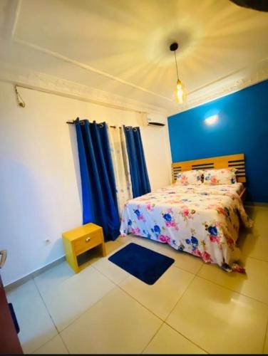 ein Schlafzimmer mit einem Bett und einer blauen Wand in der Unterkunft Guesthouse & énergie in Douala