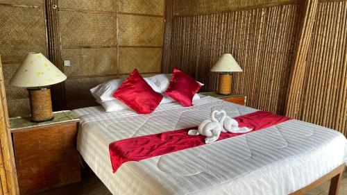 dos animales de peluche sentados en una cama con almohadas rojas en Tatai Natural Resort en Phumĭ Kaôh Ândêt