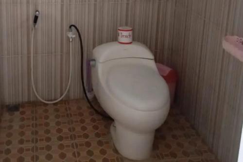 ein Badezimmer mit einem WC mit einer Tasse darüber in der Unterkunft Puri Karimunjawa RedPartner in Karimunjawa