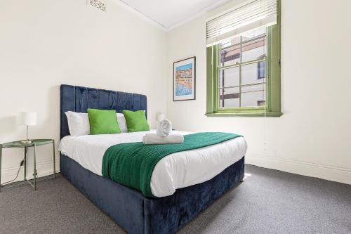 a bedroom with a large bed with green pillows at Discover The Rocks - Historical Terrace House in Sydney