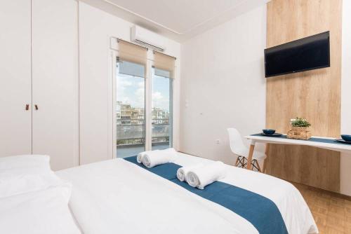 a white bedroom with a large bed and a desk at Pantheon square view 3 in Komotini