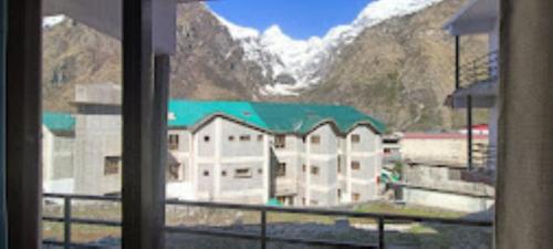 a large building with a green roof in front of a mountain at Hotel Badrinath Anant Badrinath in Badrīnāth