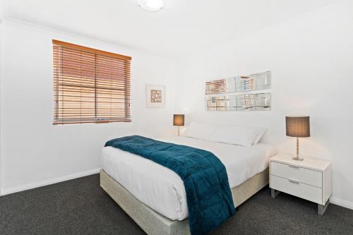 a white bedroom with a bed and two windows at Nautica Residences Hillarys in Perth