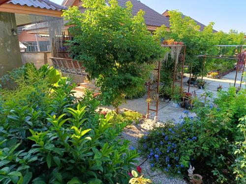 a garden with flowers and plants in front of a house at Tonpho homestay Lampangต้นโพธิ์โฮมสเตย์ in Ban Mai