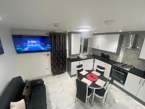a kitchen with a table and chairs and a tv on the wall at THE ROYAL BOUTIQUE OXFORD LODGE BY LONDON HEATHROW UK, PRIVATE APARTMENT OFFER's FREE PARKING, WIFI , KITCHEN & LAUNDRY SERVICES, SLEEP 8 in Hayes