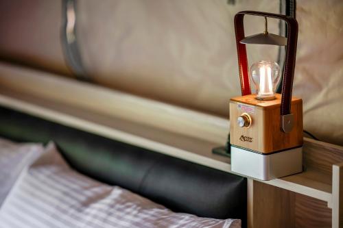 a lamp sitting on a table next to a bed at Grow Tree Glamping in Dahu