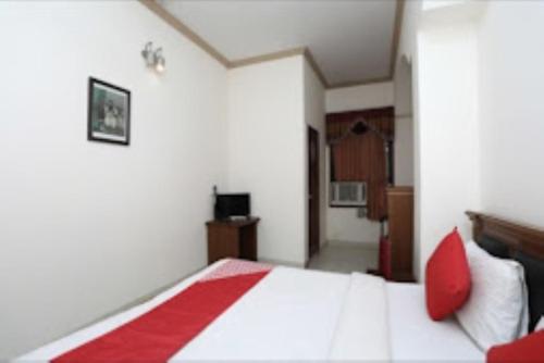 a bedroom with a white bed with red pillows at Hotel Yadu Residency Meerut in Meerut
