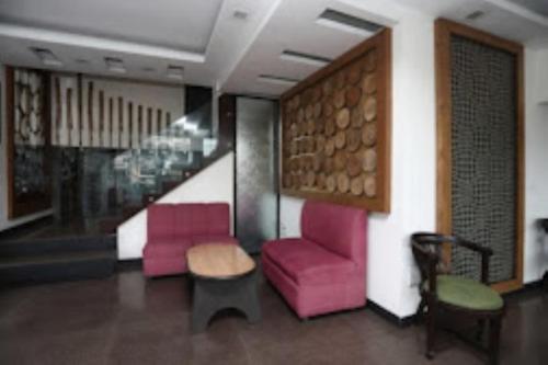 a lobby with two chairs and a table and stairs at Hotel Yadu Residency Meerut in Meerut