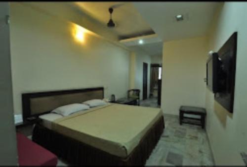 a bedroom with a bed and a flat screen tv at Hotel Yadu Residency Meerut in Meerut