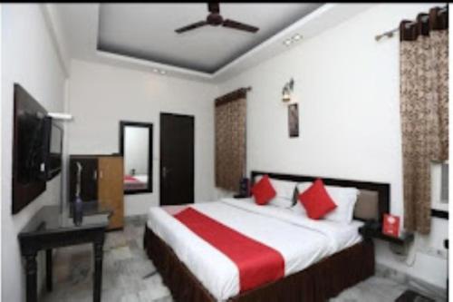 a bedroom with a bed with red pillows and a tv at Hotel Yadu Residency Meerut in Meerut
