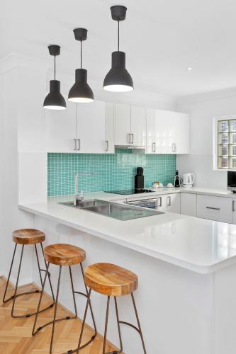 a kitchen with a white counter and two stools at Nautica Residences Hillarys in Perth
