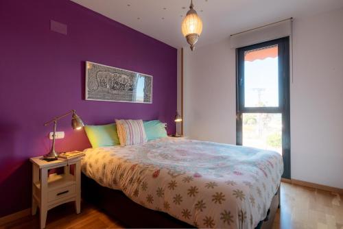 Dormitorio púrpura con cama y ventana en Apartamento LUZ DE MAR, en El Campello