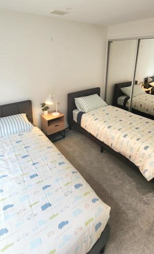 um quarto com 2 camas e uma mesa com um candeeiro em Comfy 2 bed appt in central werribee em Werribee