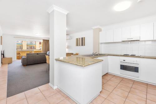 a kitchen with white cabinets and a living room at Nautica Residences Hillarys in Perth
