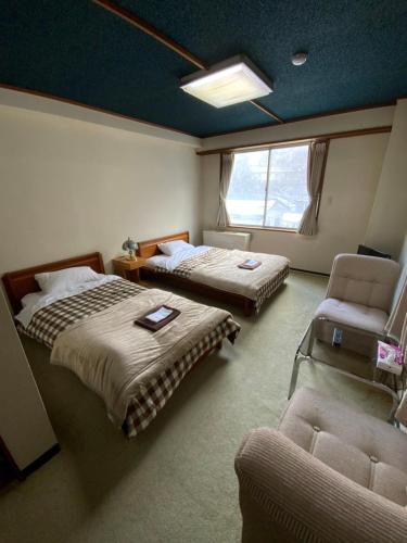 a room with two beds and a chair and a couch at ロッヂ　スガノ in Zaō Onsen