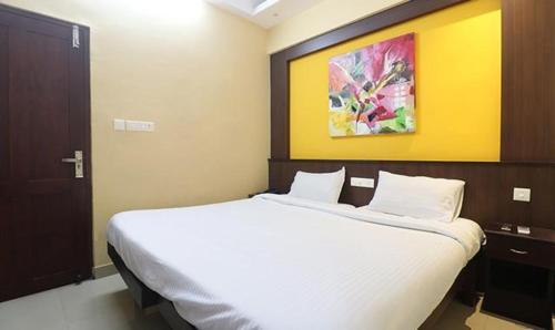 um quarto com uma grande cama branca com um quadro na parede em FabHotel Elite Inn em Trivandrum