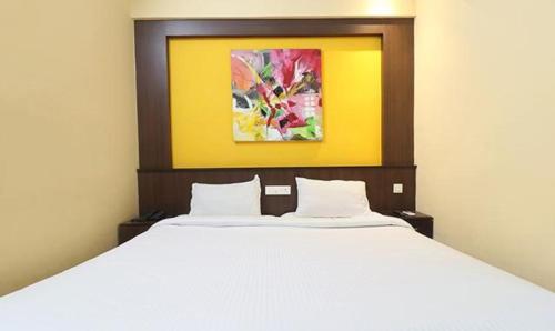 um quarto com uma cama branca e uma pintura na parede em FabHotel Elite Inn em Trivandrum