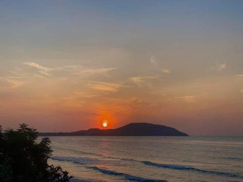 a sunset over the ocean with a mountain in the background at Hon Rom 2 Resort in Mui Ne