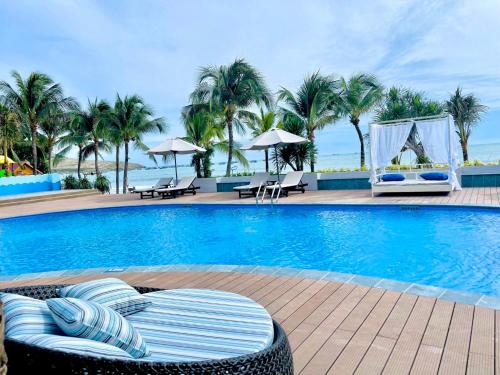 a swimming pool with chairs and tables and palm trees at Hon Rom 2 Resort in Mui Ne