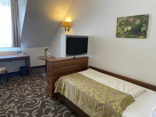 a hotel room with a bed and a flat screen tv at Hotel Winter in Schöppingen