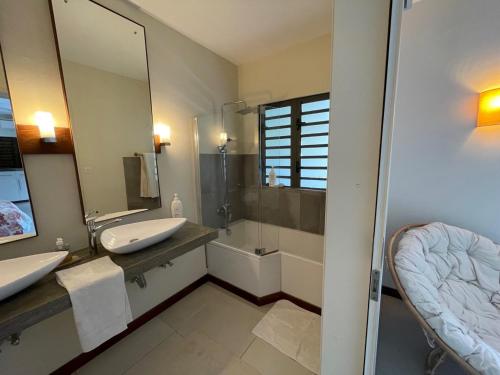 a bathroom with two sinks and a shower and a mirror at Villa Badamier in Rivière Noire
