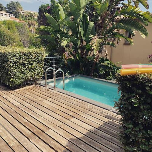 - une piscine sur une terrasse en bois à côté d'un bâtiment dans l'établissement Maison avec jardin tropical à 5 minutes de la Croisette, à Cannes
