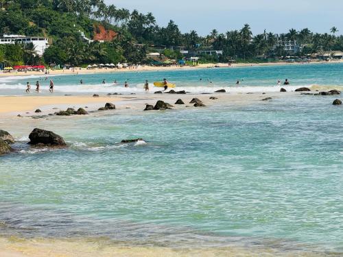 a beach with people swimming in the water at Royal Palace Mirissa in Mirissa