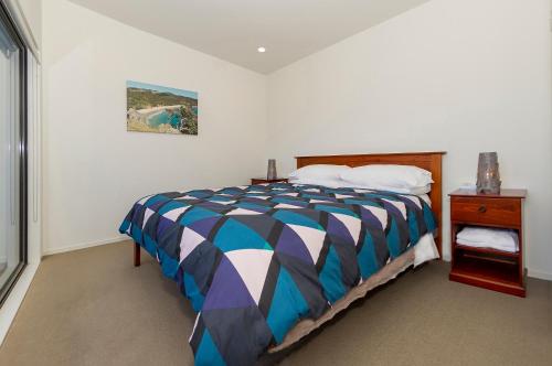 een slaapkamer met een bed met een kleurrijk dekbed bij Aqua Soleil Beachfront Apartment in Whitianga