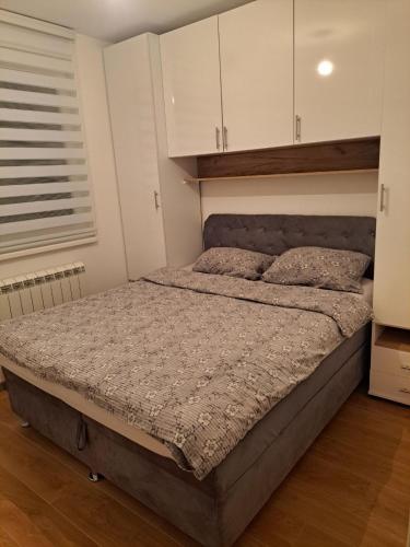 a bed in a bedroom with white cabinets at Cozy Apartment in Lukavica