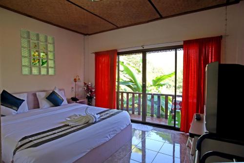 a bedroom with a bed and a large window at Phuchomjan Resort in Mae Hong Son