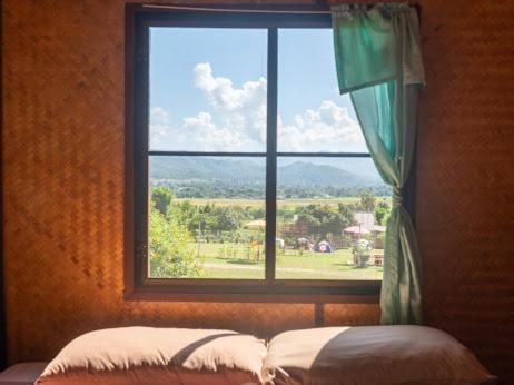 Schlafzimmer mit einem Fenster mit Blick auf ein Feld in der Unterkunft Bansuan viewpai in Pai