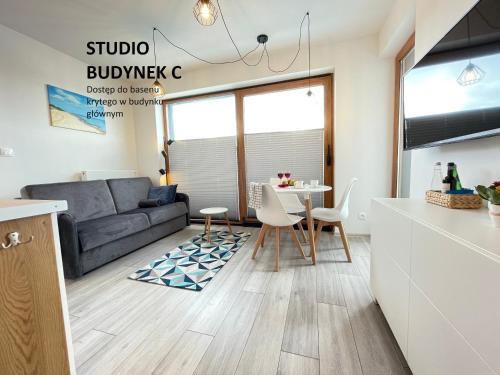 a kitchen and living room with a couch and a table at BalticSea Apartamenty in Sarbinowo