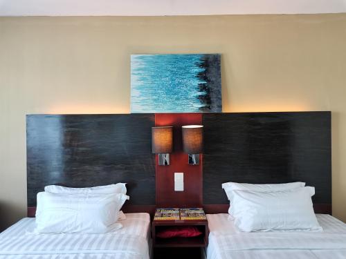 a hotel room with two beds and a painting on the wall at Greenage MingSuite 明绿时代套房 Kota Kinabalu 亚庇市中心 in Kota Kinabalu