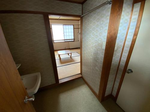 a bathroom with a urinal and a sink and a window at ロッヂ　スガノ in Zao Onsen