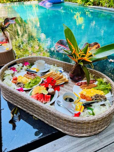 ein Tablett mit Essen auf einem Tisch neben einem Pool in der Unterkunft Frangipani Villa Kuning at Berawa in Canggu