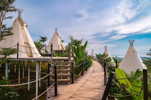 a wooden walkway leading to a group of tents at Panorama Glamping in Tân Phú