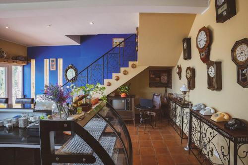a living room with blue walls and a staircase with clocks at Hacienda Resort - Mae Phim in Mae Pim