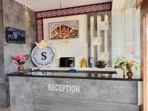 a reception desk with a clock on the wall at HOTEL SUNANDA LODGE in Belgaum